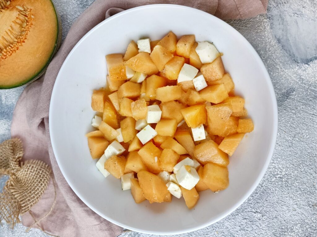 Salat aus Melone mit Mozzarella in einer weißen Schüssel